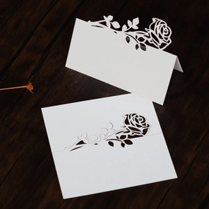 Close-up of white laser-cut rose paper place cards for elegant wedding table settings