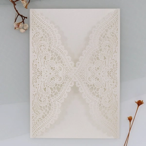 Detail of laser-cut lace wedding invitation cover in ivory pearlescent paper