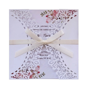 Elegant laser-cut wedding invitation with cream silk ribbon and floral insert card