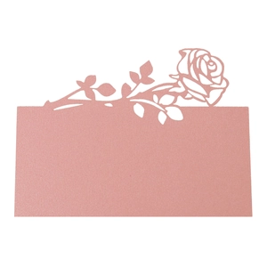 Macro detail of laser-cut rose design on pink shimmer paper wedding place cards
