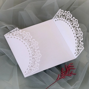Detailed laser-cut white wedding invitation card with elegant lace patterns on gray tulle