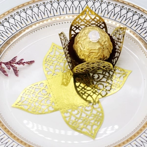 Macro detail of laser-cut gold wedding favor box for chocolate truffles with floral pattern