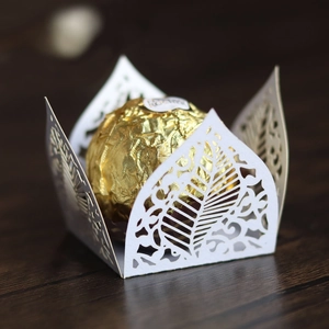 Macro detail of laser-cut white paper cupcake wrappers with elegant floral leaf patterns