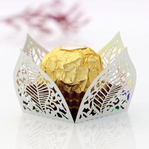 Detail of laser-cut ivory white paper cupcake wrappers with elegant leaf patterns
