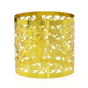 Macro detail of golden napkin ring featuring intricate laser-cut floral patterns and mesh