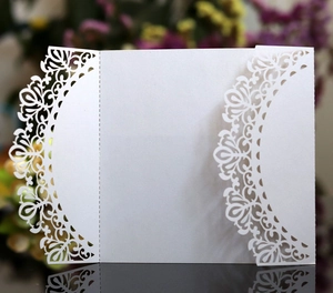 Macro detail of laser-cut white pearlescent paper wedding invitation with floral patterns