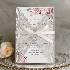 Détail de l'invitation de mariage découpée au laser argenté avec ruban et carte fleurie