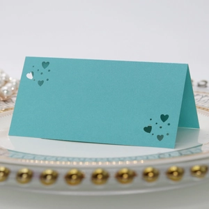 Primer plano de tarjeta de mesa azul con corazón calado sobre plato con perlas