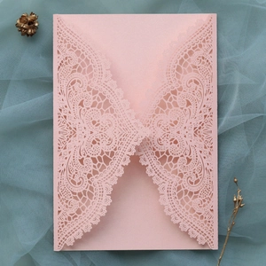 Close-up of pink laser cut wedding invitation with intricate lace hollow patterns