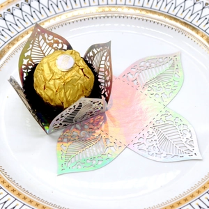 Macro detail of laser-cut iridescent hollow leaf chocolate wrappers for wedding parties