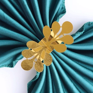 Detail shot of hollow leaf design golden napkin ring on elegant dark green satin cloth