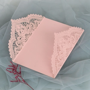 Detaillierte lasergeschnittene Spitze auf einer rosa Hochzeitseinladungskarte mit Blumen