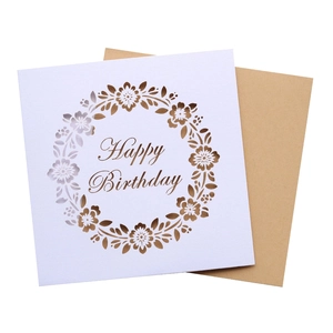 Macro detail of laser-cut floral wreath design on white Happy Birthday greeting card
