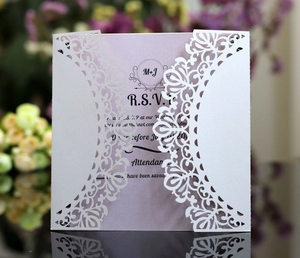 Close-up of laser-cut white lace wedding invitation with purple inner card and RSVP text