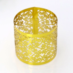 Close-up of golden laser-cut napkin ring with intricate floral vine hollow patterns
