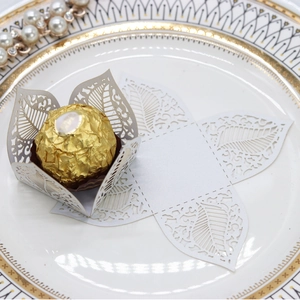 Detail of laser-cut hollow leaf candy box in pearlescent white paper with chocolate