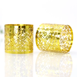 Detail of mirror gold napkin rings with laser-cut lace floral pattern on white background