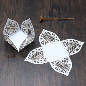 Detailed laser-cut white paper candy box with elegant leaf patterns and scrollwork texture