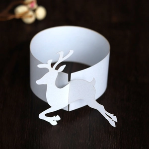 Elegant white laser cut reindeer paper napkin rings set on dark wooden surface
