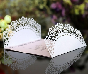 Close-up of laser cut lace invitation card with elegant floral patterns on a dark surface