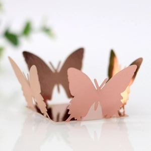 Macro view of rose gold laser-cut butterfly treat boxes with metallic hollow lace details