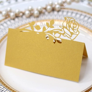 Close-up of gold laser-cut rose place card with pearlescent finish on elegant dinner plate