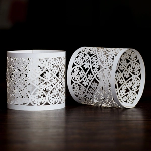 Detailed laser-cut floral pattern on white paper napkin ring for elegant wedding decor