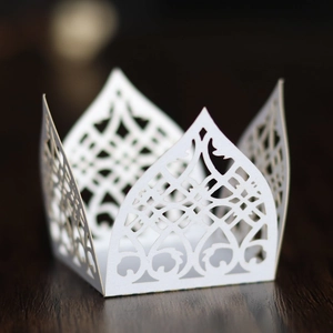 Macro shot of laser-cut white pearlescent paper wrapper with detailed floral lace patterns