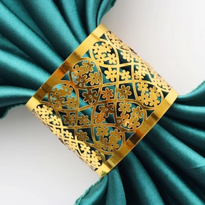 Close-up of golden hollow lace pattern napkin ring on green satin fabric detail