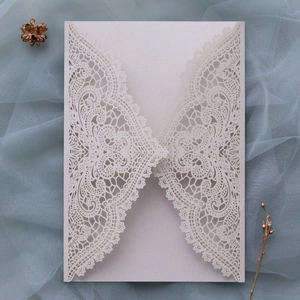 Close-up of laser-cut ivory lace wedding invitation with elegant floral hollow pattern