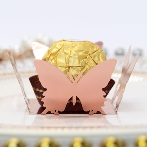 Macro shot of rose gold laser cut butterfly chocolate holder on a white ceramic plate