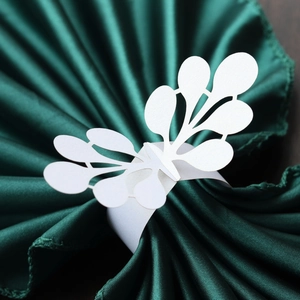 Detailed close-up of white laser-cut paper napkin ring with elegant floral lace pattern