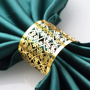 Elegant gold hollowed lace napkin ring on a dark green satin cloth for hotel decor