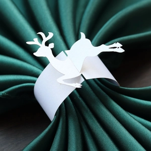 Macro shot of white pearlescent reindeer paper napkin ring on dark green fabric