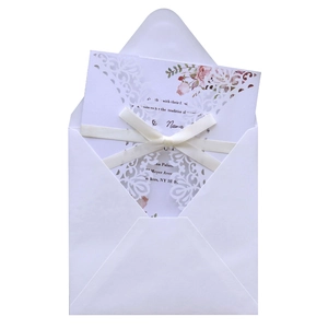 Close-up of laser-cut floral wedding invitation with white ribbon and rose printing