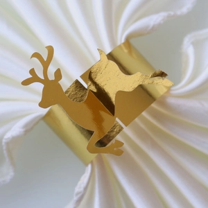 Close-up of golden reindeer mirror-finish paper napkin ring on a white fabric napkin