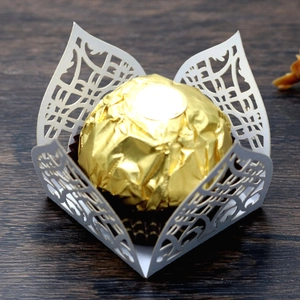 Macro view of white laser-cut hollow paper chocolate decorative holder with floral patterns