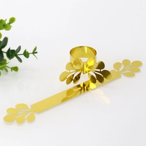 Detail of golden mirror paper napkin ring with laser-cut hollow leaf design in flat and curled view
