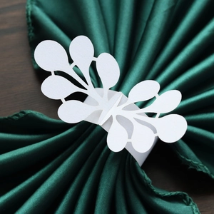 Close-up of laser-cut white paper napkin ring with floral lace pattern on green fabric