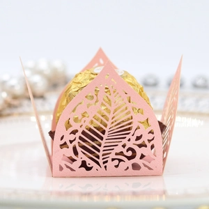 Detail of pink laser-cut pearl paper candy box with intricate hollow leaf patterns