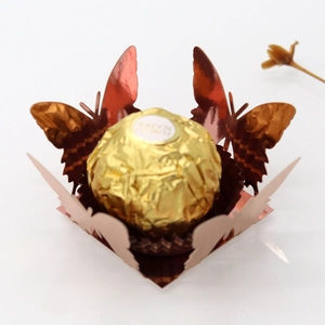 Macro detail of laser-cut gold butterfly paper candy holder with hollow wing patterns