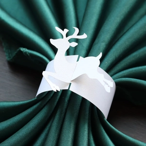 Close-up of white pearlescent reindeer paper napkin ring on green satin fabric