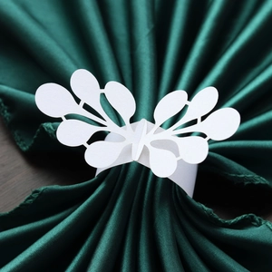 Detailed laser-cut lace pattern on a white paper napkin ring against green fabric