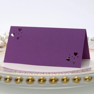 Detalle de tarjeta de mesa morada con corazones cortados por láser para bodas elegantes