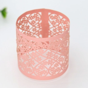 Macro view of pink pearlescent paper napkin ring with intricate laser-cut floral pattern