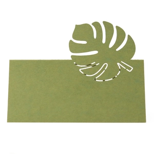 Détail du marque-place vert avec motif de feuille de monstera découpé au laser sur blanc
