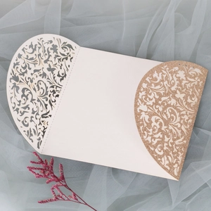 Détail macro des motifs floraux découpés au laser sur une invitation de mariage dorée