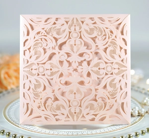 Detail of laser cut peach lace wedding invitation featuring intricate floral patterns