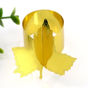 Close-up of golden maple leaf napkin ring with hollowed dot details on white background