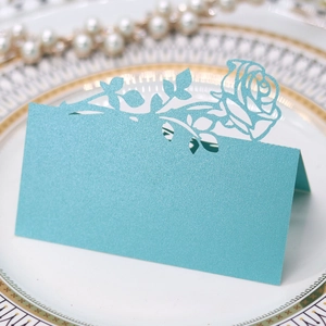 Macro detail of laser-cut rose hollow design on light blue pearlescent paper table card